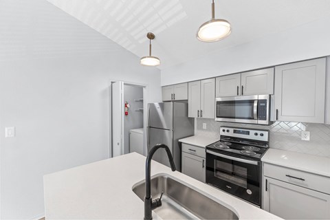 A kitchen with white cabinets and a stainless steel sink.