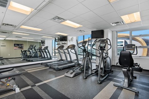 a gym with treadmills and other exercise equipment in a room with windows