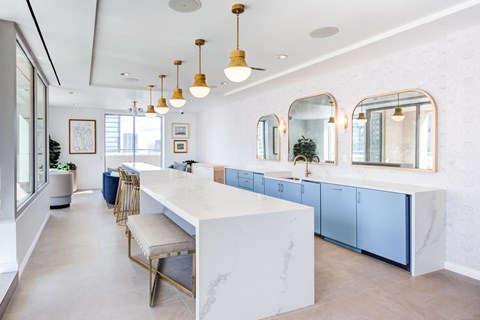 A modern kitchen with a long white island and blue cabinets.
