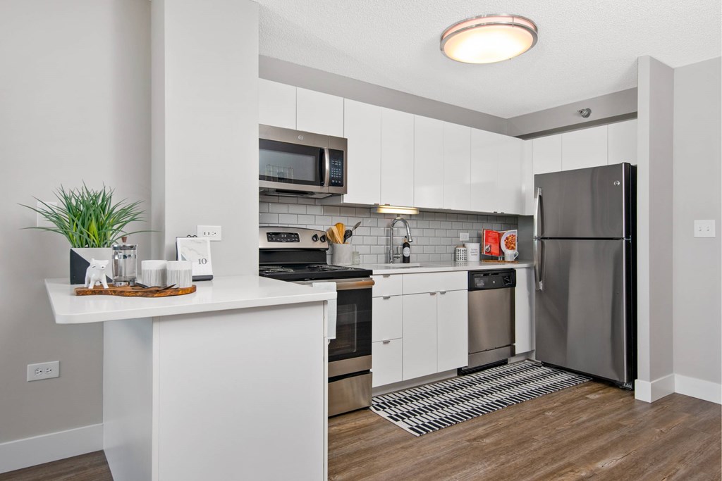 a white kitchen with stainless steel appliances and a counter top