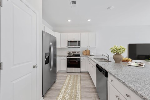 A modern kitchen with white cabinets and stainless steel appliances.