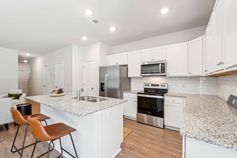 A kitchen with white cabinets and a granite countertop.
