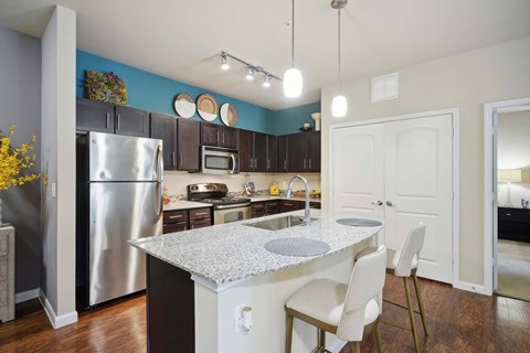 A kitchen with a table and chairs in front of it.