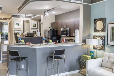 A modern kitchen with a bar area and a dining table set for two.