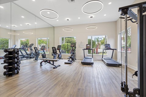 a gym with cardio machines and weights on a wooden floor
