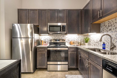 A kitchen with dark wood cabinets and stainless steel appliances.