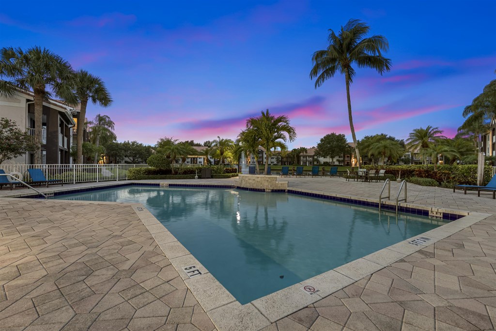 a swimming pool with palm trees and a building in the background