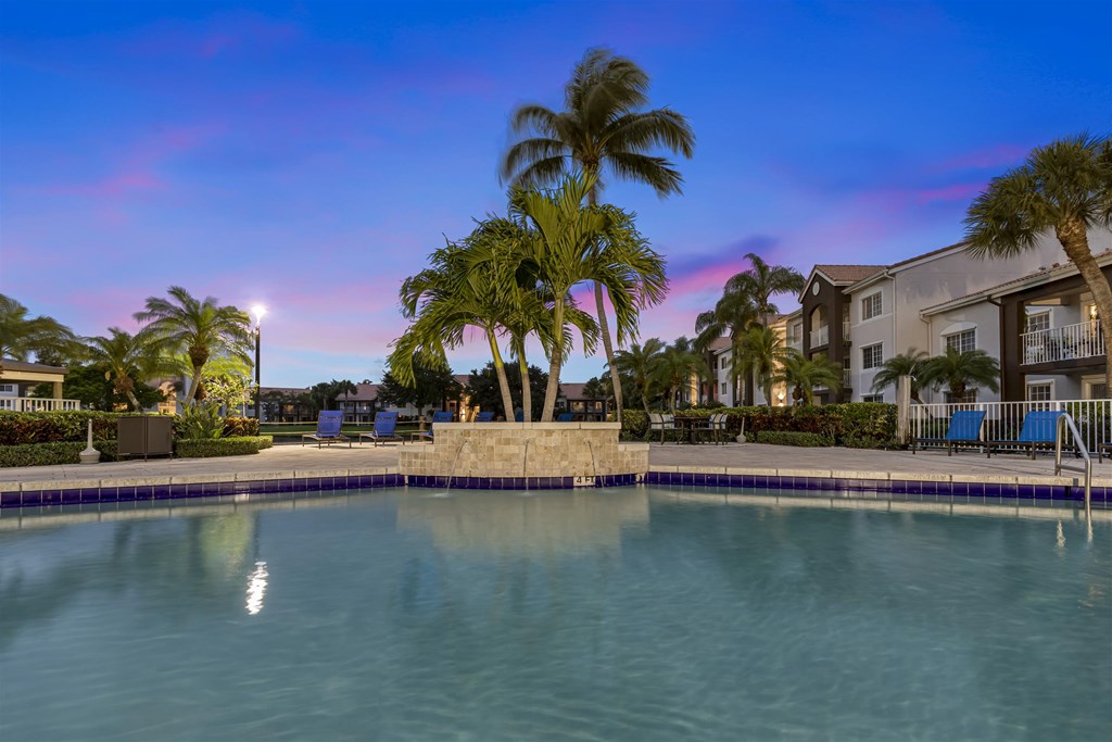 a large swimming pool with palm trees in front of a building