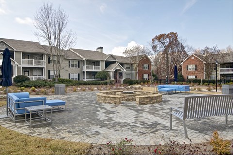an outdoor patio with a fire pit and benches in front of an apartment building