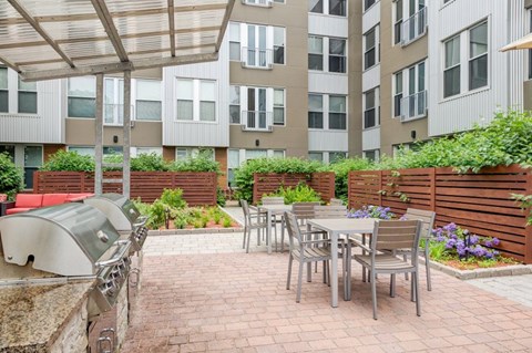 A patio with a table and chairs is surrounded by a brick wall and a wooden fence.