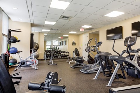 A gym with a variety of exercise equipment including treadmills, stationary bikes, and weight machines.
