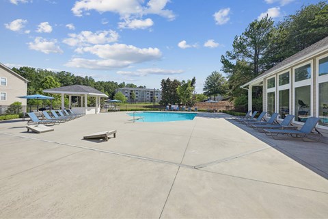 A large outdoor swimming pool with sun loungers and a pavilion.