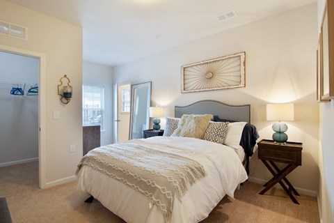 A bedroom with a large bed and a lamp on a side table.