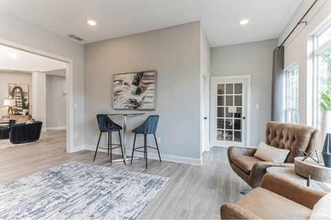 A modern living room with a dining area and a large abstract painting on the wall.