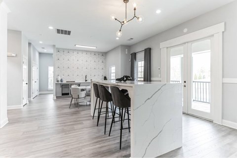 A kitchen with a marble island and a dining table with chairs.