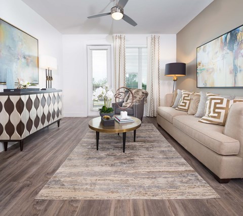 A living room with a beige sofa, a coffee table, and a painting on the wall.