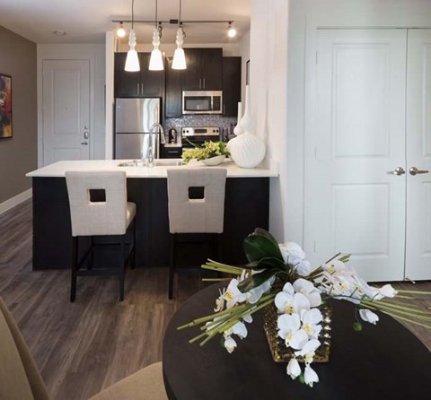 A kitchen with a black table and white chairs.