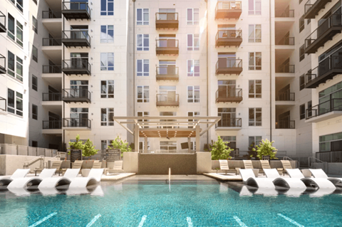 A large pool in front of a multi-story apartment building.