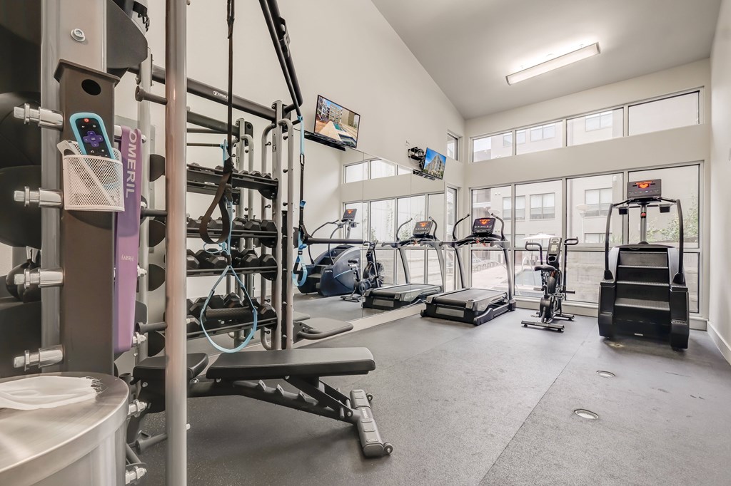 A gym with a variety of equipment including treadmills, weights, and exercise machines.