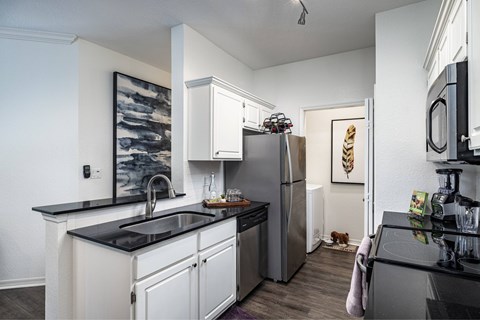 A kitchen with a black counter top and white cabinets.
