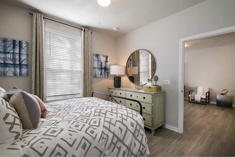 A bedroom with a patterned bedspread and a dresser with a mirror.