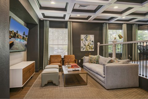 A living room with a grey couch, a coffee table, and a painting on the wall.