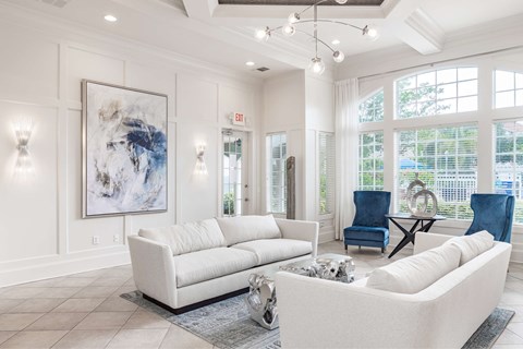 A living room with a white couch and a large abstract painting on the wall.