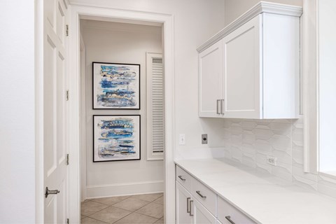 A white kitchen with a white counter top and white cabinets.