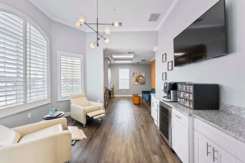 A modern living room with a long white sofa and a grey kitchen area.