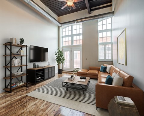 A living room with a brown leather couch and a wooden floor.