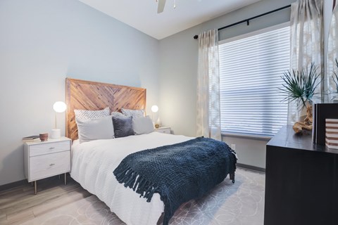 A bedroom with a bed, nightstand, and window.