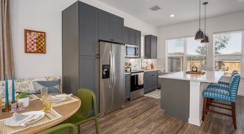 A modern kitchen with a dining table set for two.