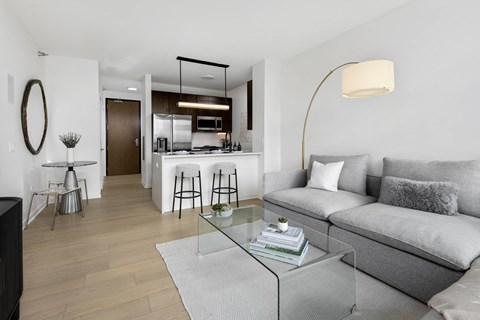 A modern living room with a grey sofa and a glass coffee table.