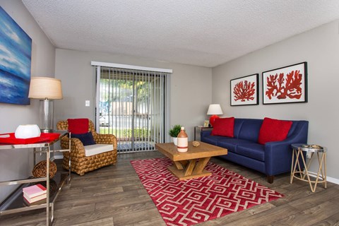 A living room with a blue couch and a red and white rug.