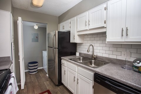 A kitchen with white cabinets and a black fridge.