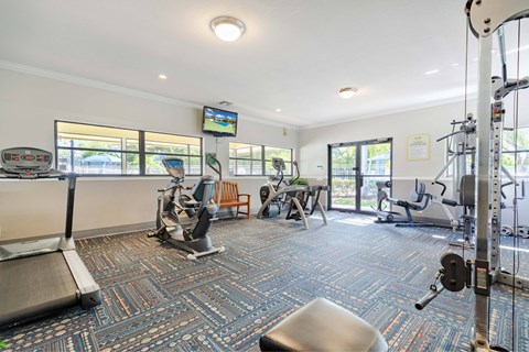 A gym with a variety of equipment including treadmills, weights, and exercise machines.