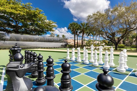 A giant chess set is set up on a green and blue checkered field.
