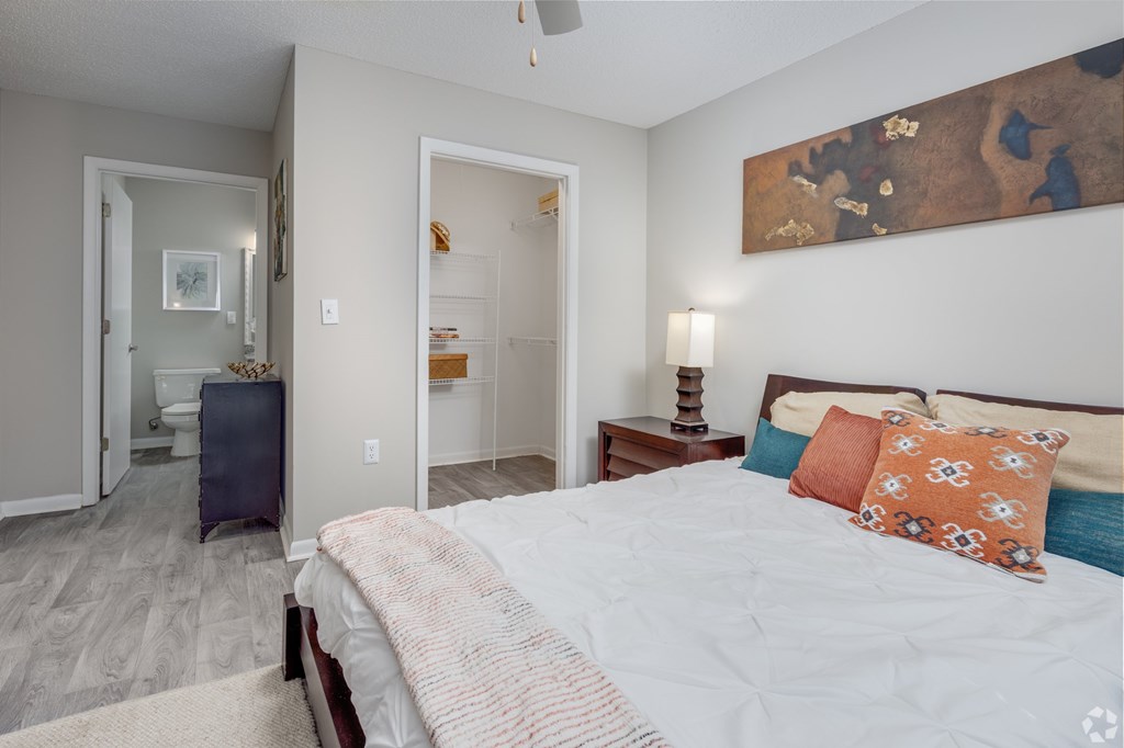 A bedroom with a bed, a nightstand, and a painting on the wall.
