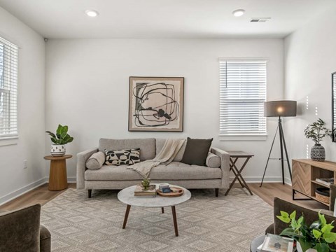 A living room with a grey couch, a coffee table, and a painting on the wall.
