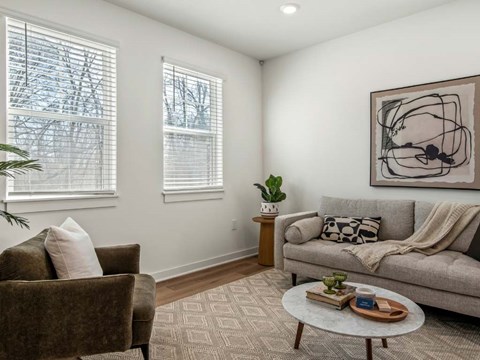 A living room with a couch, chair, and a painting on the wall.