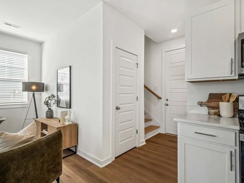 A kitchen with white cabinets and a wooden floor.