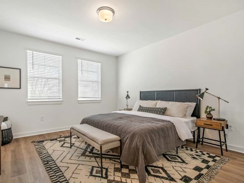 A bedroom with a bed, bench, and rug.