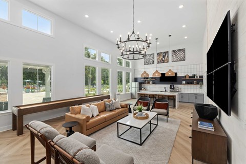 A modern living room with a large couch, a coffee table, and a flat-screen TV mounted on the wall.