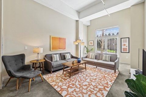 A living room with a grey couch, a black chair, a wooden coffee table, and a large painting on the wall.