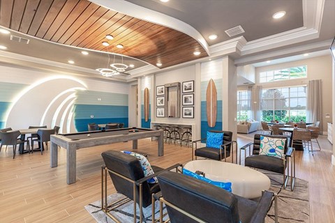 A room with a pool table and a surfboard on the wall.