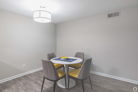 A dining room with a round table and four chairs.