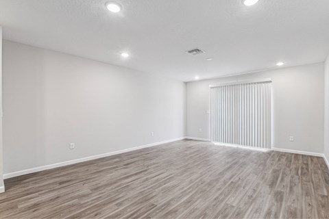 A spacious room with wooden flooring and white walls.