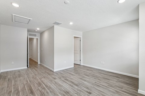 A spacious room with light wood flooring and white walls.