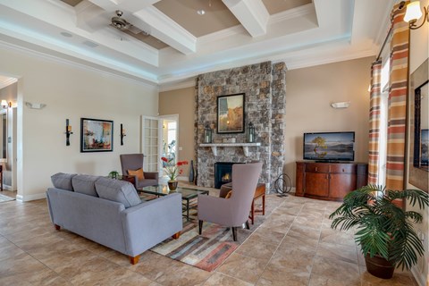 A living room with a grey couch, a fireplace, and a painting on the wall.