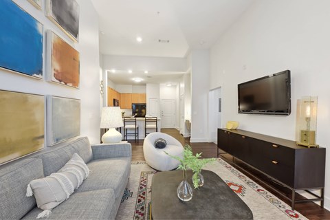 A living room with a grey couch and a large painting on the wall.